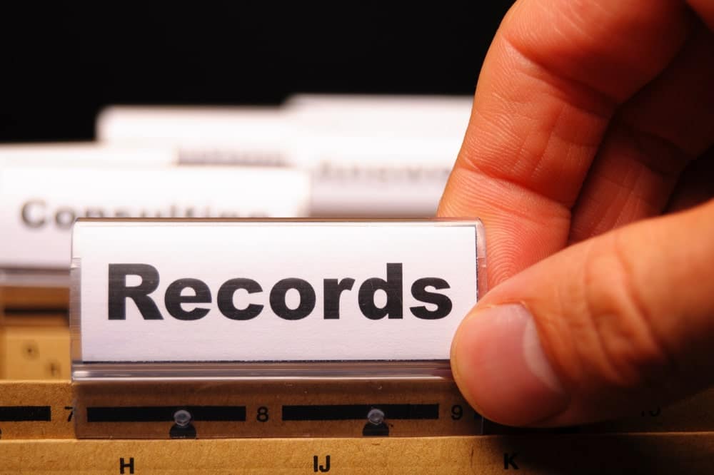 Hand holding a file tab labeled records representing search for property ownership records