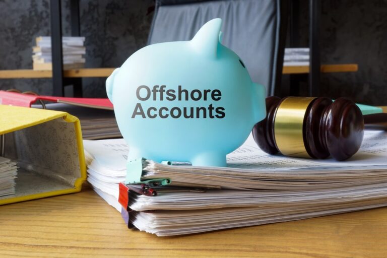 Image is of a piggy bank labeled offshore accounts placed on financial documents and legal files, concept of how asset searches identify indicators of hidden or offshore assets