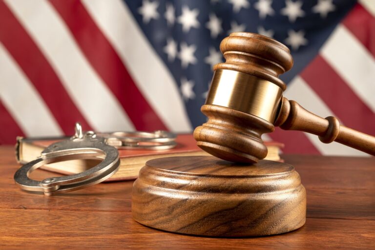 Image is of a judge’s gavel beside handcuffs and legal books in front of an American flag, illustrating how court outcomes influence what appears in WA background reports.