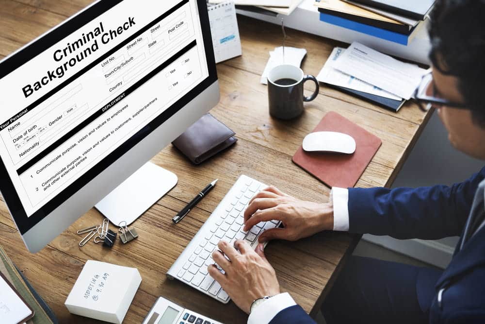 Image is of a professional reviewing a criminal background form on a computer, concept of WA background checks and digital record verification